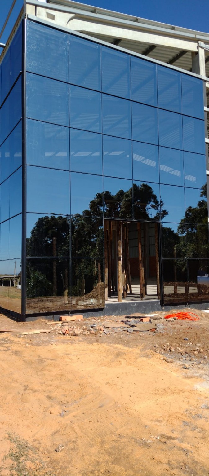 Fachada envidraçada com sistema de pele de vidro, perfis de alumínio e painéis de vidro refletivo.
